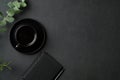 Coffee break concept. Black office desk table with cup of coffee, paper notebook, pen, eucalyptus on leather background. Flat lay Royalty Free Stock Photo