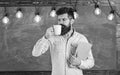 Coffee break concept. Man with beard on calm face in classroom. Teacher in eyeglasses holds book and mug of coffee or Royalty Free Stock Photo