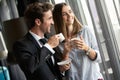 Couple of young colleagues in formal wear standing at workplace, drinking coffee near window Royalty Free Stock Photo