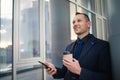 Happy smiling businessman using modern smartphone near office early in the morning, successful employer to close a deal. Royalty Free Stock Photo
