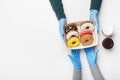 Coffee break for lunch during covid-19 pandemic. Customer in rubber gloves takes a box of glazed donuts and two cups of