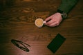 Coffee break. Man hand keep a cup of coffee on a wooden table. Phone and glasses. Business situation.