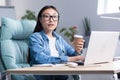 Coffee break in the office. Young beautiful Asian business woman drinking coffee at a desk Royalty Free Stock Photo
