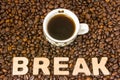 Coffee break photo. Cup with brewed coffee is on table, which filled with roasted coffee beans, next to word break. Idea to design