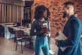 Two cheerful young people holding coffee cups and talking while standing in office Royalty Free Stock Photo