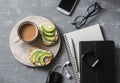 Coffee break during working hours. Flat lay business workplace with notebook, tablet, phone, glasses. Coffee and sandwich with cre