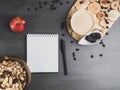 Coffee break in the workplace. White cup of coffee, apple, mix of nuts in wooden bowl, notepad, pen on grey background, top view Royalty Free Stock Photo