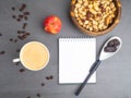 Coffee break in the workplace. White cup of coffee, apple, mix of nuts in wooden bowl, notepad, pen on grey background, top view Royalty Free Stock Photo