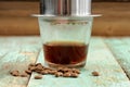 Coffee brewed in small metal French drip filter on wooden table Royalty Free Stock Photo