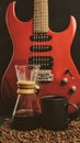 A coffee brewing jug, a red electric guitar, a black coffee mug on a dark black background Royalty Free Stock Photo