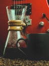 A coffee brewing jug, a red electric guitar, a black coffee mug on a dark black background. Royalty Free Stock Photo