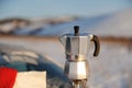 Coffee brewing in moka pot on a gas burner on the car trunk outdoor in winter snow landscape