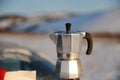 Coffee brewing in moka pot on a gas burner on the car trunk outdoor in winter snow landscape