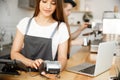 Coffee business concept - beautiful female barista giving payment service for customer with credit card and smiling Royalty Free Stock Photo