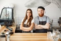 Coffee Business Concept - Positive young bearded man and beautiful attractive lady barista couple in apron looking at Royalty Free Stock Photo