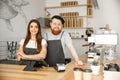 Coffee Business Concept - Positive young bearded man and beautiful attractive lady barista couple in apron looking at Royalty Free Stock Photo