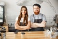 Coffee Business Concept - Positive young bearded man and beautiful attractive lady barista couple in apron looking at Royalty Free Stock Photo