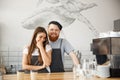 Coffee Business Concept - Positive young bearded man and beautiful attractive lady barista couple enjoy working together Royalty Free Stock Photo