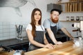 Coffee Business Concept - Positive young bearded man and beautiful attractive lady barista couple in apron looking at Royalty Free Stock Photo