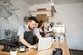 Coffee business concept - young handsome bearded bartender, barista or manager working and planing in laptop at modern Royalty Free Stock Photo