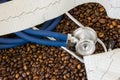 Coffee or caffeine and heart arrhythmias irregular heartbeat. Stethoscope and ECG tape on background of coffee beans. Effect and