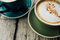 Coffee cappuccino in a green cup on a saucer. Two cups coffee on a wooden table Royalty Free Stock Photo