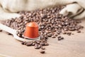 Coffee capsule on wooden spoon and coffee beans desaturated Royalty Free Stock Photo