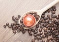 Coffee capsule on wooden spoon and coffee beans close up Royalty Free Stock Photo