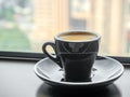 Coffee in ceramic black cup and round dish beneath at window light view Royalty Free Stock Photo
