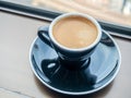 Coffee in ceramic black cup and round dish beneath at window light view Royalty Free Stock Photo