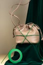 Coffee-colored handbag made from an artificial leather on a podium covered with green velvet on a beige background. Composition of