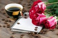 Coffee concept. roses and coffee. cup of coffee and a bouquet of roses on a wooden table. morning coffee and note. copy spaces. Royalty Free Stock Photo