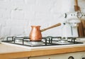 Coffee copper pot on the stove at bright kitchen, morning routine
