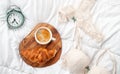 Coffee with croissant, alarm clock and girls underwear in the bed at home