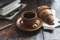 Coffee with croissant on cloth and notebooks with pencil