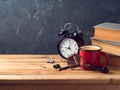 Coffee cup, alarm clock and old books on vintage wooden table Royalty Free Stock Photo