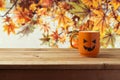 Coffee cup as jack o lantern pumpkin on wooden table over autumn background Royalty Free Stock Photo