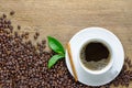 Coffee cup with beans, cinnamon stick and green leaf on wood table Royalty Free Stock Photo
