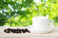 Coffee cup and beans on wood table over blurred tree background Royalty Free Stock Photo