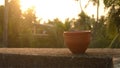 Coffee cup Bhar in sunset sunlight. Summer fresh cool look. Muddy mud tea cup made of clay for hot drink on roof beam of a
