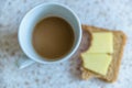 Coffee cup and bitten rye bread and cheese sandwich closeup view