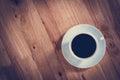 Coffee cup with black coffee on wooden table (top view)