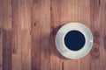 Coffee cup with black coffee on wooden table (top view)