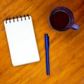 Coffee cup and blank page of notepad with pen on wooden table. White paper notebook top view photo Royalty Free Stock Photo
