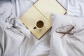 Coffee cup, book, reading glasses on bed Royalty Free Stock Photo