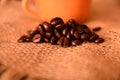 Coffee cup with burlap sack of roasted beans on rustic table Royalty Free Stock Photo