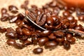 Coffee cup with burlap sack of roasted beans on rustic table Royalty Free Stock Photo