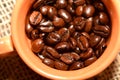 Coffee cup with burlap sack of roasted beans on rustic table Royalty Free Stock Photo