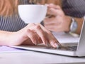 Coffee cup in businesswoman`s hand. Young woman working with documents and laptop close-up. Royalty Free Stock Photo