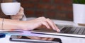 Coffee cup in businesswoman`s hand. Young woman working with documents and laptop close-up Royalty Free Stock Photo